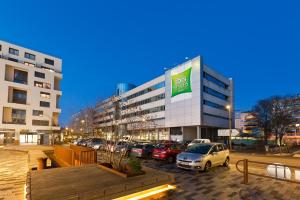a parking lot with cars parked in front of a building at ibis Styles Massy Op&eacute;ra in Massy
