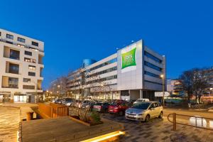 a parking lot with cars parked in front of a building at ibis Styles Massy Opéra in Massy