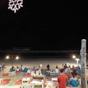 a group of people sitting on the beach at night at Sunrise Resort- Koh Phangan - SHA Extra Plus in Haad Rin