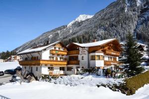 a building in the snow with a mountain at Apart-Pension Wasserfall in Neustift im Stubaital