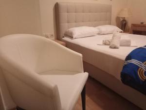 um quarto com 2 camas e uma cadeira branca em Omiros em Piraeus