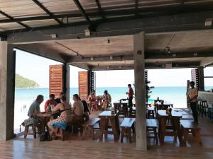 a group of people sitting at tables at a beach restaurant at Sunrise Resort- Koh Phangan - SHA Extra Plus in Haad Rin