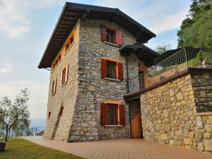 uma casa de pedra com janelas vermelhas e uma varanda em IseoLakeRental - La Stallina - Monte Isola em Monte Isola