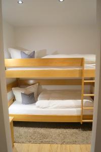 2 Etagenbetten in einem Zimmer mit weißen Kissen in der Unterkunft Gästehaus Greiter - Sommer Bergbahnen inklusive in Oberstdorf