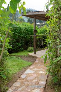 einen Gehweg in einem Garten mit einer hölzernen Pergola in der Unterkunft Karungi Camp in Rubuguli