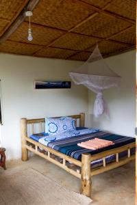 a wooden bed in a room with a ceiling at Karungi Camp in Rubuguli