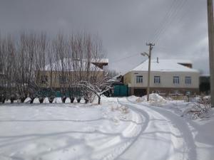 uma estrada coberta de neve em frente a uma casa em TwinHouse Karakol em Karakol
