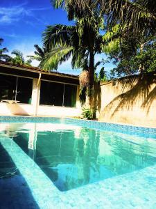 una piscina frente a una casa con palmeras en Takeo's House, en Boicucanga