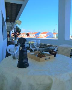a table with two wine glasses and a box at Surf & Guest Lorena´s House in Ribeira Grande