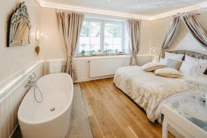 a bedroom with a tub and a bed and a window at OLEANDER SUITEN großzügig wohnen mit besonderem Charme in Trausdorf