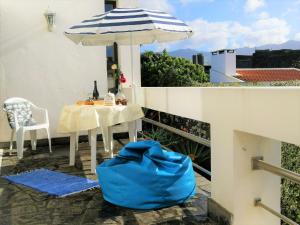 een tafel met een paraplu en een blauwe tas op een balkon bij Surf & Guest Lorena´s House in Ribeira Grande +27 foto's