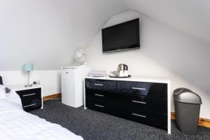 a bedroom with a bed and a tv on the wall at The Garage @ The Old Vicarage in Swansea