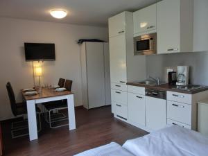 a room with a desk and a kitchen with white cabinets at Fewo mit Terrasse in Gelbensande