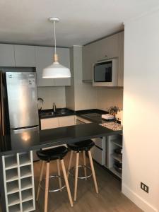 a kitchen with a black counter and two bar stools at 8,Clínica Las Condes, 3 personas in Santiago