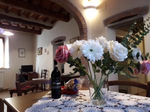 een vaas met bloemen op een tafel met een fles wijn bij Dinas House Tuscany Holidays in Terricciola