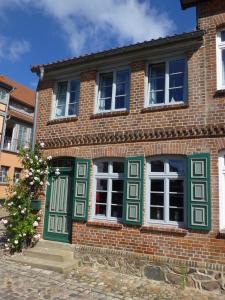 プラウ・アム・ゼーにあるAltes Fischerhausの緑と白の窓のあるレンガ造りの家