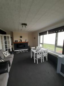 a living room with a couch and a table and chairs at Seabreeze in Littlestone-on-Sea
