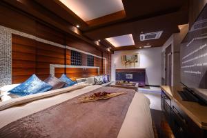 a bedroom with a large bed and a flat screen tv at HOTEL ZEN KOHOKU in Yokohama