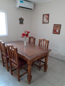 una mesa de madera con 4 sillas y un jarrón con flores. en Departamento 4 Complejo Sol de Oeste, en San Juan