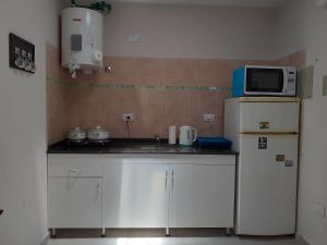 Una pequeña cocina con microondas y nevera. en Departamento 4 Complejo Sol de Oeste, en San Juan 11 fotos más