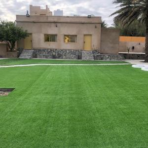 una casa con un césped verde delante de ella en The Wadi Inn, en Al Ḩamrāʼ