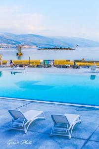 a swimming pool with two chairs in front of the water at MIRAMAR Apartman in Novi Vinodolski