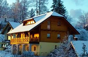 een groot houten huis met een met sneeuw bedekt dak bij Apartma Zgodba in Cerklje na Gorenjskem