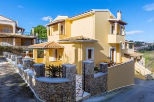 a yellow house with a stone wall at Louisa's Summer House in Kastanéa
