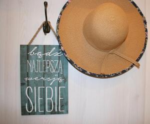 un sombrero de paja colgado en una pared junto a una señal en Apartamenty Turystyczne WillkasSen, en Giżycko