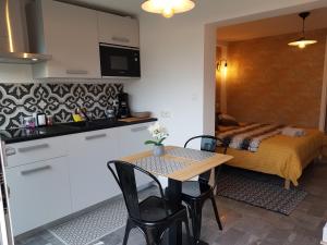a small kitchen and a table in a room with a bed at Le P'tit gousset, à 100 m de la mer in Donville-les-Bains