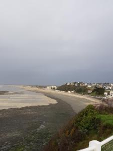 a view of a beach with the ocean and a white fence at Le P'tit gousset, à 100 m de la mer in Donville-les-Bains +3 photos