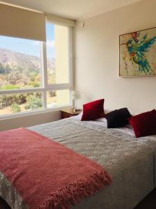 a bedroom with a bed with red pillows and a window at Papudo LPV in Papudo