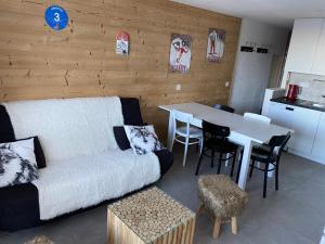 Plagne Centre - Immeuble Le Mustag - Wifi في آيم لا بْلانيِ: غرفة معيشة مع أريكة وطاولة مع كراسي