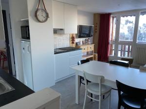 een keuken met een witte tafel en een klok aan de muur bij Plagne Centre - Immeuble Le Mustag - Wifi in Aime La Plagne