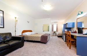 ein Schlafzimmer mit einem Bett, einem Sofa und einem Schreibtisch in der Unterkunft Elliotts Kapiti Coast Motor Lodge in Paraparaumu Beach
