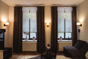 ケムニッツにあるathome IHR Apartmentのリビングルーム(ソファ付)、ブラインド付きの窓2つが備わります。
