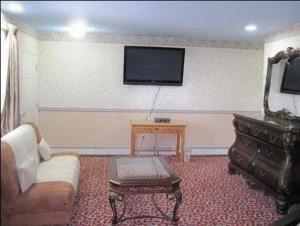 ein Wohnzimmer mit einem Sofa und einem TV an der Wand in der Unterkunft The Parsippany Inn and Suites in Morris Plains