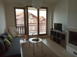 a living room with a couch and a tv at Emerald Buddha Apartment in Bansko