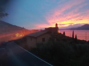a house on the side of a road with a sunset at Locanda San Marco in Torri del Benaco