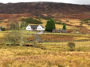 a white house in the middle of a field at Springburn Farmhouse in Spean Bridge