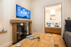a living room with a table and a tv on a wall at Sandpiper, apartment across from the beach in Marazion
