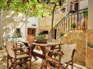 un patio con mesa de madera y sillas en Joya Village House en Agios Leon