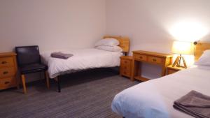 mały pokój z 2 łóżkami i krzesłem w obiekcie Canyon Cottage w mieście Pont-Nedd-Fechan