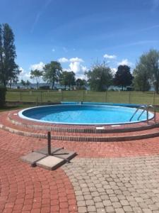 una piscina circular en un parque con suelo de ladrillo en B-Home Resort en Zamárdi