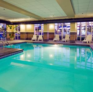 a swimming pool in a hotel with chairs and tables at Holiday Inn Express Hotel & Suites Columbia-Fort Jackson by IHG in Columbia