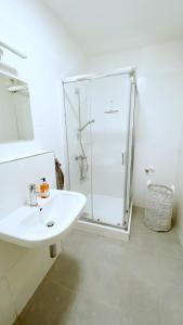 a white bathroom with a shower and a sink at Mezonetový apartmán ve skandinávském stylu in Rokytnice nad Jizerou