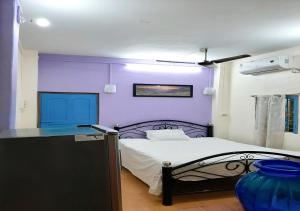 1 dormitorio con paredes moradas y 1 cama con mesa en Dden Vennell BnB -Metro Access- en Calcuta