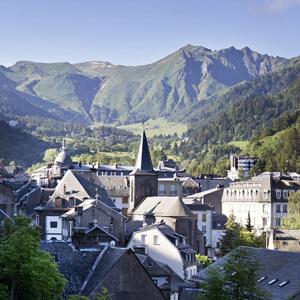 une ville avec des bâtiments et des montagnes en arrière-plan dans l'établissement La Villa des Thermes, à Le Mont-Dore 5 autres photos