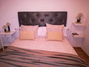 - une chambre avec un grand lit et des oreillers roses dans l'établissement Apartamento en el centro de la ciudad 75 metros, à Villanueva de la Serena