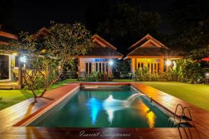 a swimming pool in front of a house at night at Sawasdeepai River Resort in Pai